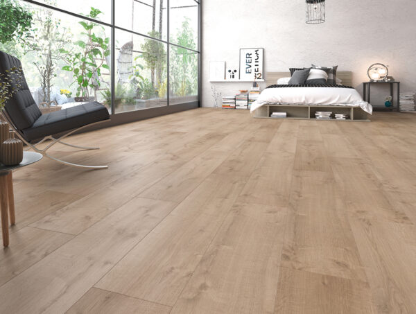 Albendo, vloeren specialist - Een moderne slaapkamer met grote ramen, Laminaat Warm Vergrijsd vloeren, een laag bed met wit beddengoed, zwarte loungestoel, kamerplanten en boeken bij een witte muur. Natuurlijk licht vult de ruimte.