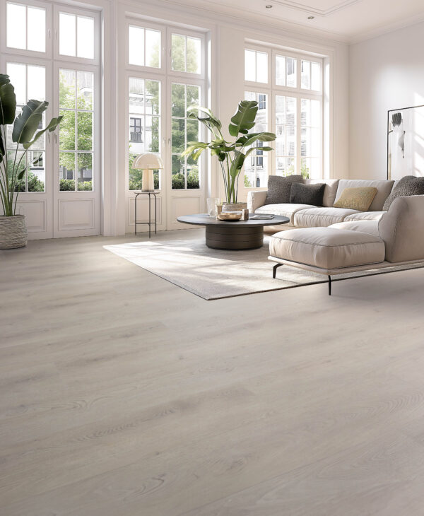 Albendo, vloeren specialist - Een lichte, moderne woonkamer met grote ramen, Click PVC 2800 (harde klik) woestijnvloer, een crèmekleurige sofa, een ronde salontafel en groene potplanten. Natuurlijk licht vult de ruime, minimalistische ruimte.