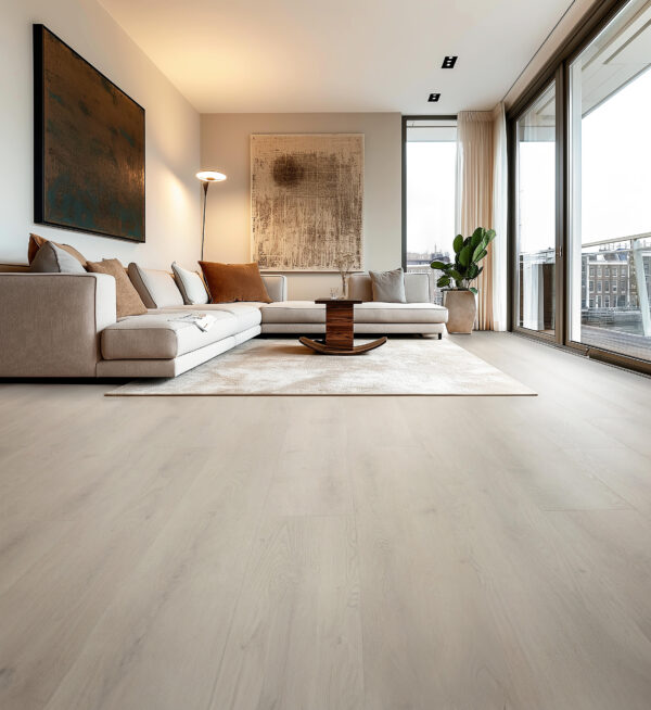 Albendo, vloeren specialist - Een moderne woonkamer met Click PVC 2800 (harde klik) woestijnvloer, een beige sofa met bruine en crèmekleurige kussens, abstracte muurkunst, een hoge plant, een salontafel en grote ramen die natuurlijk licht binnenlaten.