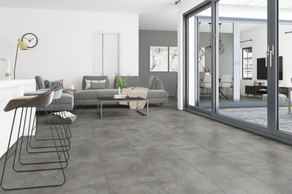 Albendo, vloeren specialist - Moderne open leefruimte met Click Tegel PVC 5501 (harde klik) Beton Antra vloeren, minimalistische meubels, barkrukken bij een aanrecht, grote glazen schuifdeuren en een neutrale inrichting met planten en ingelijste kunst.