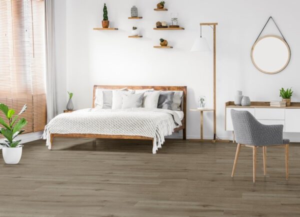 Albendo, vloeren specialist - Minimalistische slaapkamer met een houten bed, wit beddengoed, zwevende planken met planten, een grijze stoel aan een bureau, ronde spiegel, plant in pot en Natural Oak Smoked Click PVC 5103 (harde klik) vloer met zonlicht dat door de raamgordijnen naar binnen schijnt.