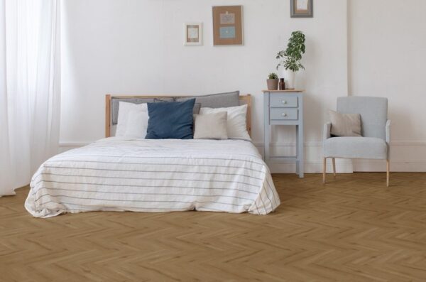 Albendo, vloeren specialist - Een minimalistische slaapkamer met een bed met een wit gestreept dekbed, een blauw nachtkastje, een potplant, muurkunst en een lichtgrijze fauteuil, allemaal op een Click Visgraat 5200 (harde klik) vloer in naturel eiken donker.
