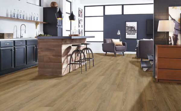 Albendo, vloeren specialist - Moderne open keuken en woonkamer met Click PVC 5604 (harde klik) Olympia Pine Natural vloeren, donkere kasten, een houten eiland met twee krukjes, fauteuils, bank en grote ramen voor natuurlijk licht.