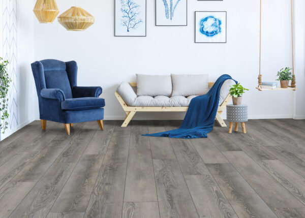 Albendo, vloeren specialist - Moderne woonkamer met Olympia Pine Natural Click PVC 5604 vloer, een blauwe fauteuil, lichthouten bank met witte kussens, blauwe plaids, kamerplanten, hanglampen, schommel en ingelijst kunstwerk op een witte muur.