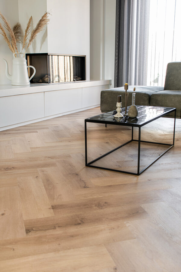 Albendo, vloeren specialist - Moderne woonkamer met Click PVC Visgraat 5400 (Rigid Click) Prestige Oak Natural vloeren, een zwart metalen salontafel met decor, groene sofa, witte kruik met pampagras en ingebouwde open haard onder een groot raam.
