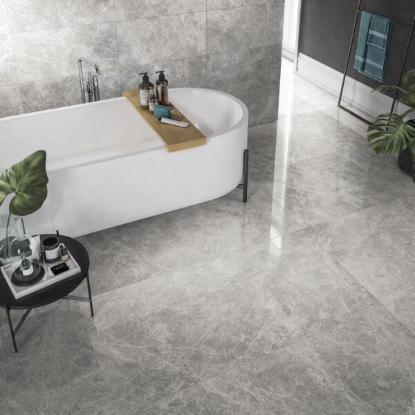 Albendo, vloeren specialist - Moderne badkamer met Kale Corinthian Beige 60x120cm tegels, een wit vrijstaand bad met een houten dienblad, een klein zwart rond bijzettafeltje met spa-artikelen en een groene plant in de hoek.
